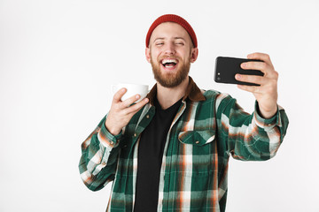 Naklejka premium Portrait of handsome man wearing plaid shirt holding credit card and cell phone, while standing isolated over white background