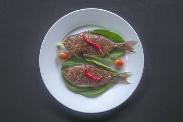 smoked, fried fish on a white plate with spices