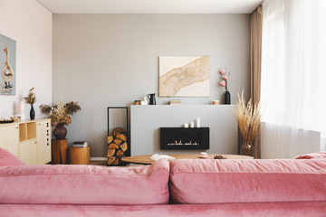Bright grey living room interior with wooden accents and pastel pink couch