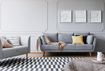 Real photo of a spacious living room interior with to sofa, triptych and striped carpet