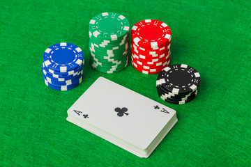 Casino chips and playing cards on green table