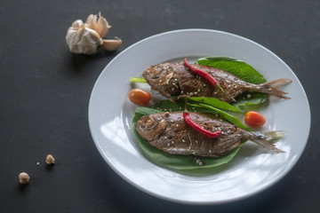 smoked, fried fish on a white plate with spices