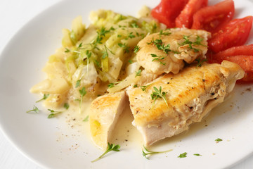 stewed chicken breast fillet with celery leek vegetables and tomatoes, healthy ketogenic low carb diet for slimming on a white plate, close up