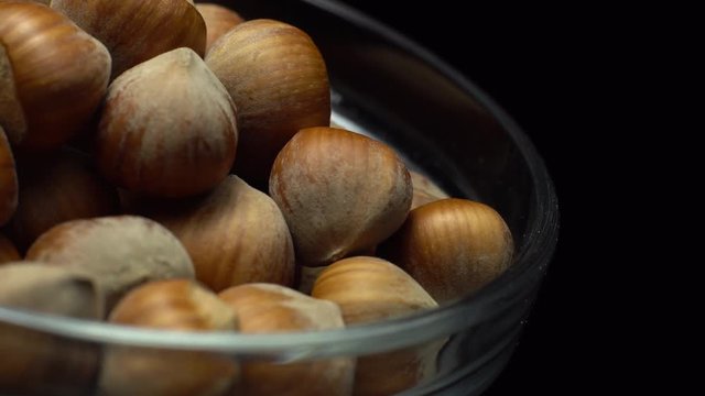 Hazel nuts in nutshell. Rotation. Closeup.    Walnuts in a bowl. Selective focus. Black background. Studio shot. Healthy food concept.