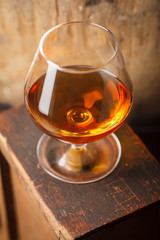 Glass of brandy near a barrel