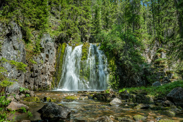Fototapeta na wymiar Waterfall flushing down a green moss covered rock wall