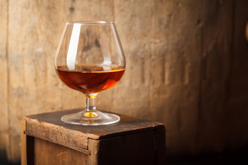 Glass of brandy near a barrel - obrazy, fototapety, plakaty
