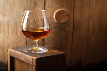 Glass of brandy near a barrel