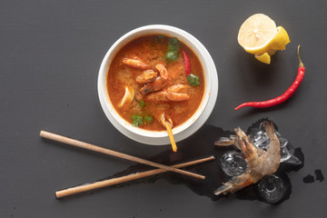 Tom Yam with shrimps and lemon on a dark background