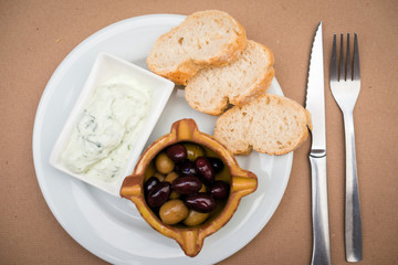Fresh olives with butter and slices of baguette