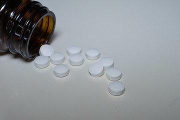Jar with white pills on white background