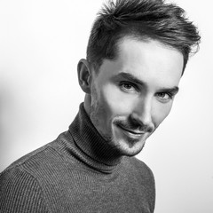 Handsome young elegant man in grey golf. Black-white studio photo.