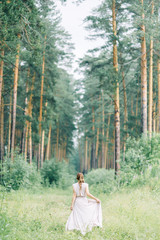 Boudoir photo shoot of the bride in the woods with a bouquet. Flying dress and beautiful girl in the Park.