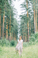 Boudoir photo shoot of the bride in the woods with a bouquet. Flying dress and beautiful girl in the Park.