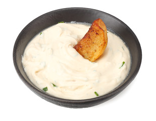 Fried potato wedges with garlic sauce in black bowl isolated on white background