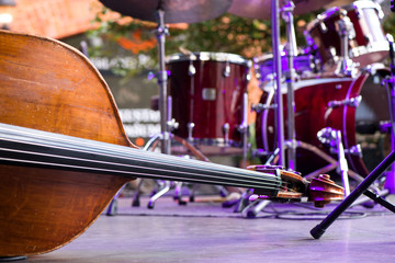 Wooden cello or violin on stage prepared for playing. Classical instruments, piano, drums in...