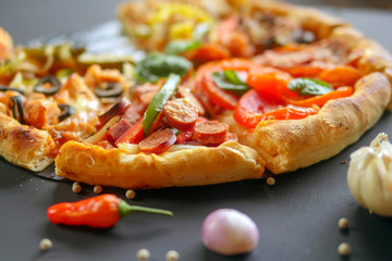 Pizza with ham, orange and red pepper, cherry tomatoes, black olives, mushrooms and fresh basil. Italian pizza. Symbolic image. Concept for a tasty and healthy meal. Selective focus. Close up.