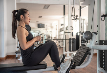Happiness pretty woman exercise with cable weight machine in gym. - Image