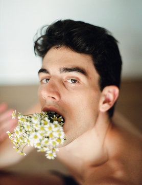 Young man with bunch of flowers in mouth