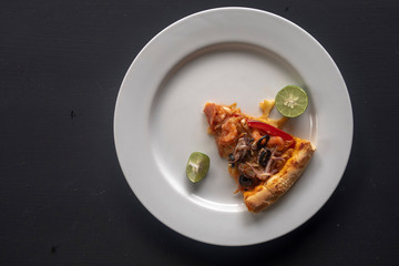 Seafood pizza slice on white plate on dark background