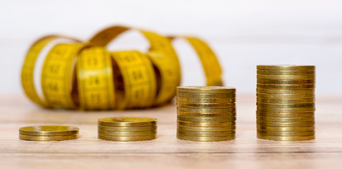 Money savings concept - web banner of gold coins with measuring tape