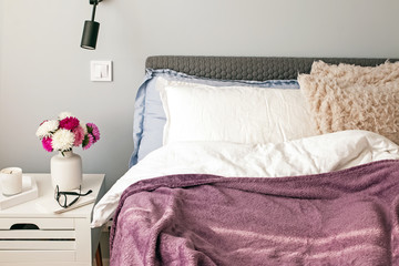 Modern bedroom in the morning with flowers and coffee on the nightstand