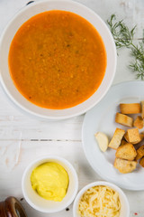 fish soup mashed potatoes with crackers on a white wooden background. The background is decorated with vegetables.