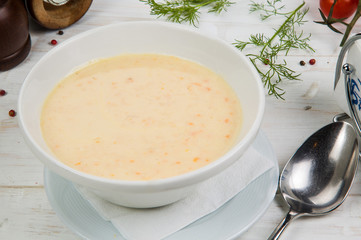 Cream soup with mussels on a white wooden background. The background is decorated with vegetables.