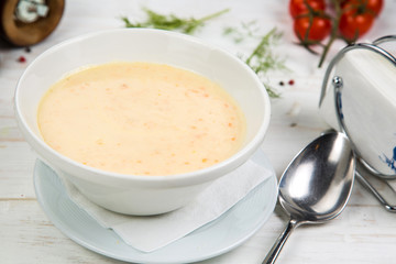 Cream soup with mussels on a white wooden background. The background is decorated with vegetables.