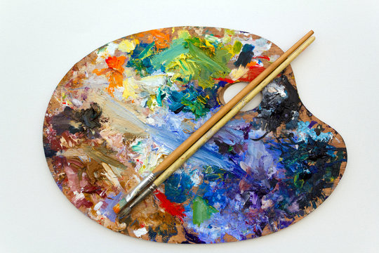Vibrant multi-coloured artists oil or acrylic paints palette on textured white paper with paintbrushes