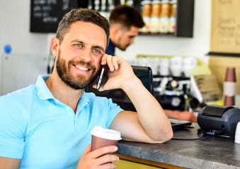 Drink coffee while waiting. Waiting for you. Man smartphone order coffee in cafe. Coffee break concept. Coffee take away option for busy people. Man mobile conversation cafe barista background
