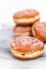 Traditional German or Austrian fried donuts with no hole, so called Krapfen, Berliner or Pfannkuchen with cinnamon sugar and filled with rose hip, raspberry or strawberry jam, party or carnival food