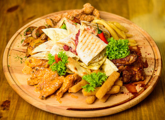 Meat snack for group friends. Tasty delicious snacks. Restaurant food. Snack for beer. Wooden board french fries fish sticks burrito and meat steak served with salad. Enjoy your meal. Pub menu snack