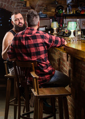 Hipster bearded man spend leisure with friend at bar counter. Strong alcohol drinks. Opening hours till last visitors. Friday relaxation in bar. Men relaxing at bar. Friends relaxing in bar or pub