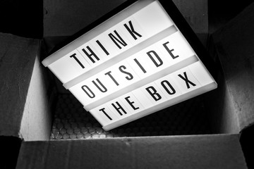 Think outside the box message on lightbox coming out of a parcel