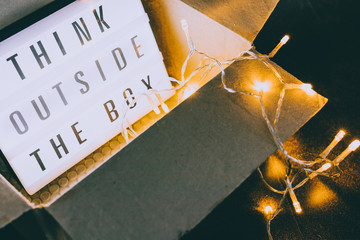 Think outside the box message on lightbox coming out of a parcel with fairy led lights