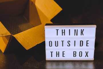 Think outside the box message on lightbox coming out of a parcel