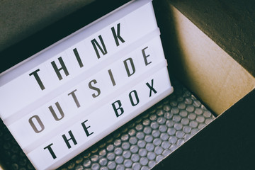 Think outside the box message on lightbox coming out of a parcel