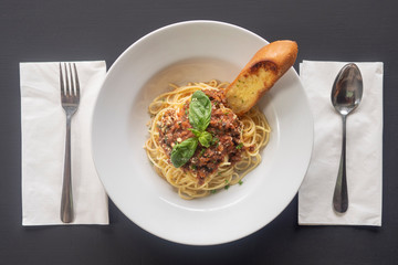 Pasta bolognese on a white plate on a dark background