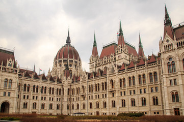 Fototapeta na wymiar Daytime view of historical building of Hungarian Parliament, aka Orszaghaz, with typical symmetrical architecture and central dome on Danube River embankment in Budapest, Hungary, Europe