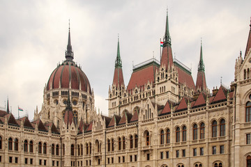 Fototapeta na wymiar Daytime view of historical building of Hungarian Parliament, aka Orszaghaz, with typical symmetrical architecture and central dome on Danube River embankment in Budapest, Hungary, Europe