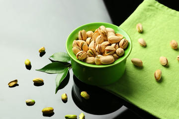 Bowl with tasty pistachio nuts on light background