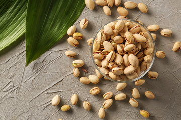 Dessert bowl with tasty pistachio nuts on grey background