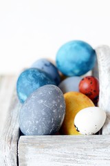 Colored Easter eggs in a wooden basket on a white background. Happy easter. Easter decoration.