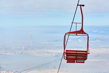 Empty old wooden chairlift against out of focus aerial urban area. Brasov, Romania.