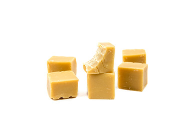 Tasty yellow Fudge squares, bite taken from one of the cubes, isolated on white, studio shot. Sugar addiction, temptation concept.