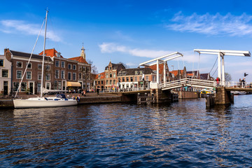 HARLEM, NETHERLANDS - APRIL 14, 2018: Spaarne river with boats, famous tourist landmark Gravestenenbrug bridge and houses in Haarlem, Netherlands.