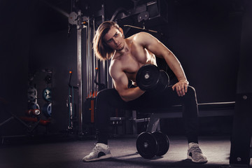 Fototapeta na wymiar Athletic man working out with dumbbells in the gym.