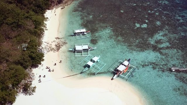 Aerial view of tropical island beach with people, boats and turquoise sea. Palawan May 2017. 4K resolution