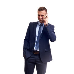 Fototapeta premium Portrait of a smiling young business man using smartphone and holding cup of coffee isolated on a white background